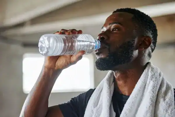 Hydration: The Secret Ingredient for a Toned Stomach and Enhanced Fitness 1 Image of man drinking water to improve hydration Eccles after work out.